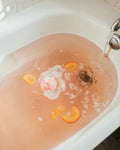 Creamy Peach Rush bath bomb turning the bath blush-peach with peach slices